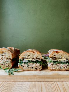 three sandwiches cut in half sitting on top of a cutting board next to each other