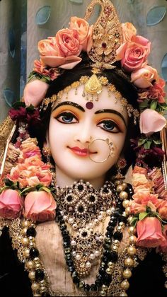 a statue with flowers around it and a face painted in gold, white and red