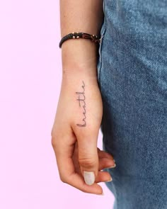 a woman's hand with a small tattoo on her left wrist and the word faith written in cursive font