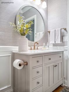 a bathroom with a sink, mirror and two rolls of toilet paper on the counter