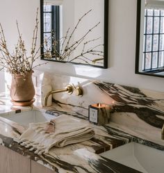 a bathroom with marble counter tops and two mirrors on the wall, one has a candle in it