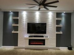 a living room with a fireplace and tv mounted on the wall, along with built - in shelving units