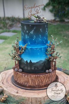 a three tiered cake decorated with blue and green frosting, stars and trees