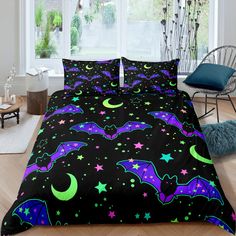 a black bed with purple and green bat designs on the comforter is in front of a window