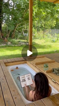 a woman sitting in a hot tub reading a book with an open page on it