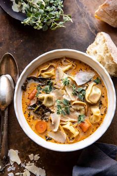 a bowl of soup with tortellini shells, carrots and parmesan cheese