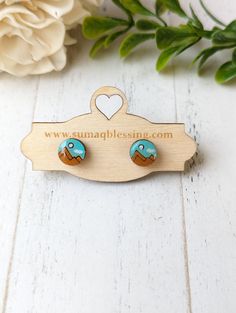 the earrings are made from wood and have turquoise colored stones on them, along with a heart - shaped wooden hanger