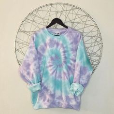 a purple and blue tie - dye shirt hanging on a wire rack next to a white wall