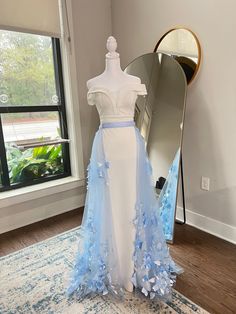 a blue and white wedding dress on display in front of a mirror with a large mirror behind it