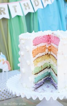 there is a multi layer cake with white frosting on the top and rainbow colored layers