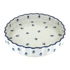 a blue and white dish with flowers on it's rim, against a white background