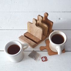 two mugs of coffee sit next to wooden cutting boards with pieces of wood on them