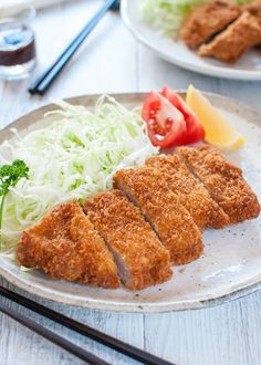 some food is on a plate with chopsticks next to it and two plates