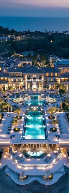 an aerial view of a resort at night with lights on the pool and surrounding buildings