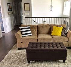 a living room filled with furniture and a brown ottoman sitting on top of a white rug