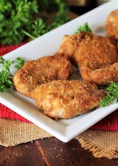 some fried chicken on a white plate with parsley