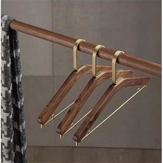 three wooden clothes hangers on a metal rod