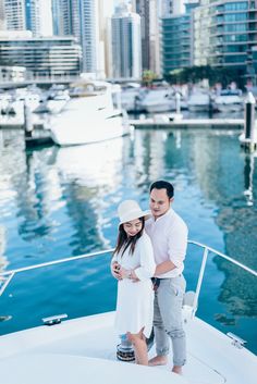 a man and woman standing on the back of a boat in front of a city