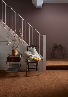 a chair sitting in front of a stair case next to a table with fruit on it