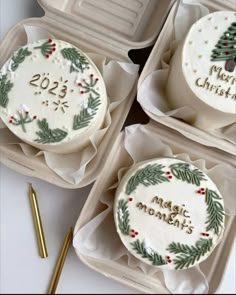 three decorated christmas cakes sitting on top of trays next to a gold fork and spoon