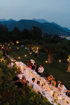 a long table with people sitting at it and lit candles on the tables in front of them