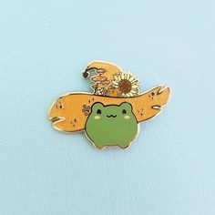 a green frog with sunflowers on it's head sitting in front of a blue background