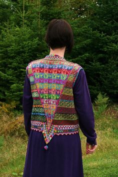 a woman standing in front of some trees wearing a purple dress with multicolored crochet