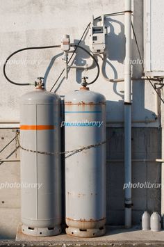 two large tanks are next to each other on the side of a building with wires