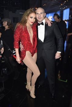 a man in a tuxedo standing next to a woman in a red dress