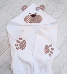 a white bear towel with brown polka dots on it's ears and paws is laying on the floor