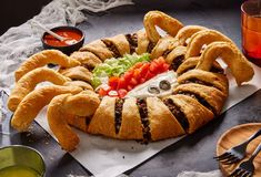 a crab shaped bread dish on a plate with dipping sauces and condiments