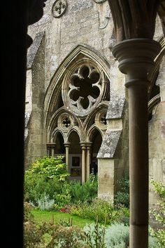 an old building with many arches and flowers in the foreground is seen through a window