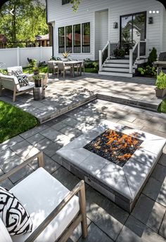 a fire pit sitting in the middle of a patio surrounded by lawn furniture and trees