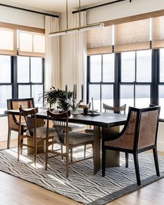 a dining room table and chairs in front of large windows