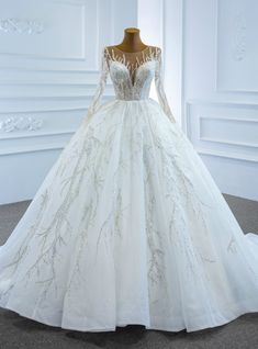 a white wedding dress with long sleeves and beadings on the bouncy