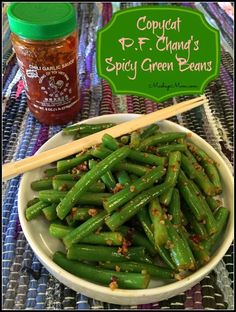 a white bowl filled with green beans next to a jar of mustard and chopsticks