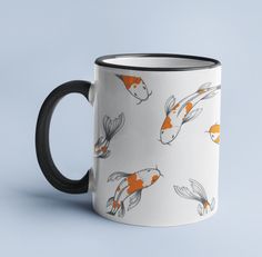 a black and white coffee mug with goldfish on it's side, against a blue background