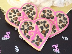 three decorated cookies in the shape of hearts on a table with pink and black decorations