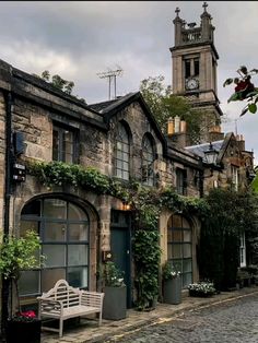 an old stone building with ivy growing on it's sides and a clock tower in the background