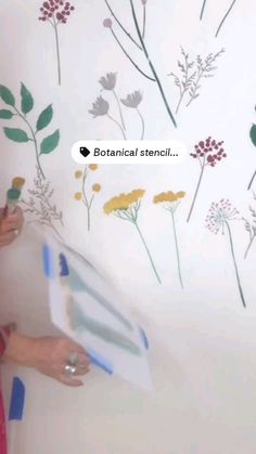 a woman is painting a wall with flowers on it and the words botanical stencil