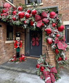 christmas decorations on the front door of a brick building with a nutcracker and wreath