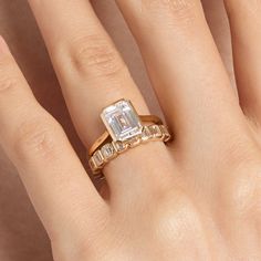 a woman's hand with an engagement ring on top of her finger and the other hand holding it