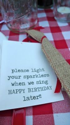 a red and white checkered table cloth with a sign that says, please light your sparklers when we sing happy birthday later