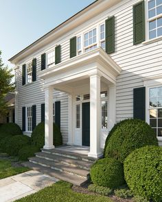 a white house with green shutters and steps leading to the front door is shown