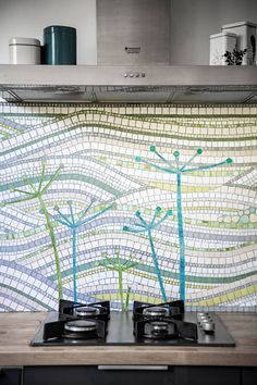 a stove top oven sitting next to a wall with plants on the back splashing through it