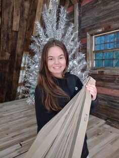 a woman is holding some kind of hammock in front of a christmas tree