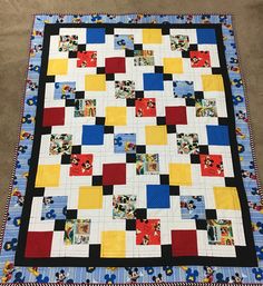 a colorful quilt on the floor in front of a carpeted area with a blue and yellow blanket