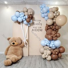 a teddy bear sitting next to a balloon arch