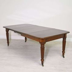 an antique dining table with two leaves on the top and one leaf at the base