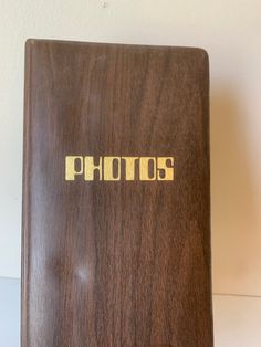 a wooden photo album with the word photos printed in gold on it's cover